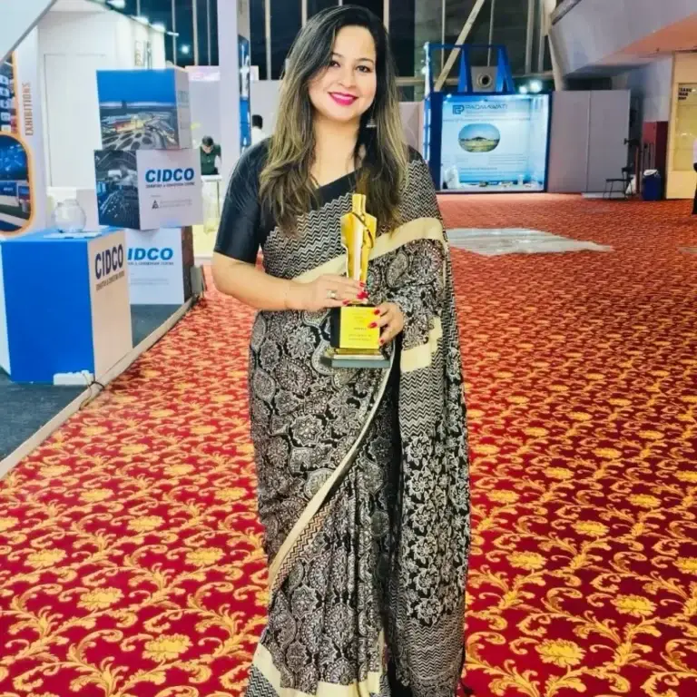 Happy customer wearing black printed Kaarigar saree while holding a trophy at an award ceremony